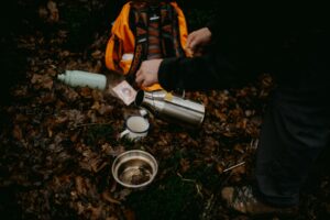 une personne versant de l'eau dans une tasse posée sur le sol