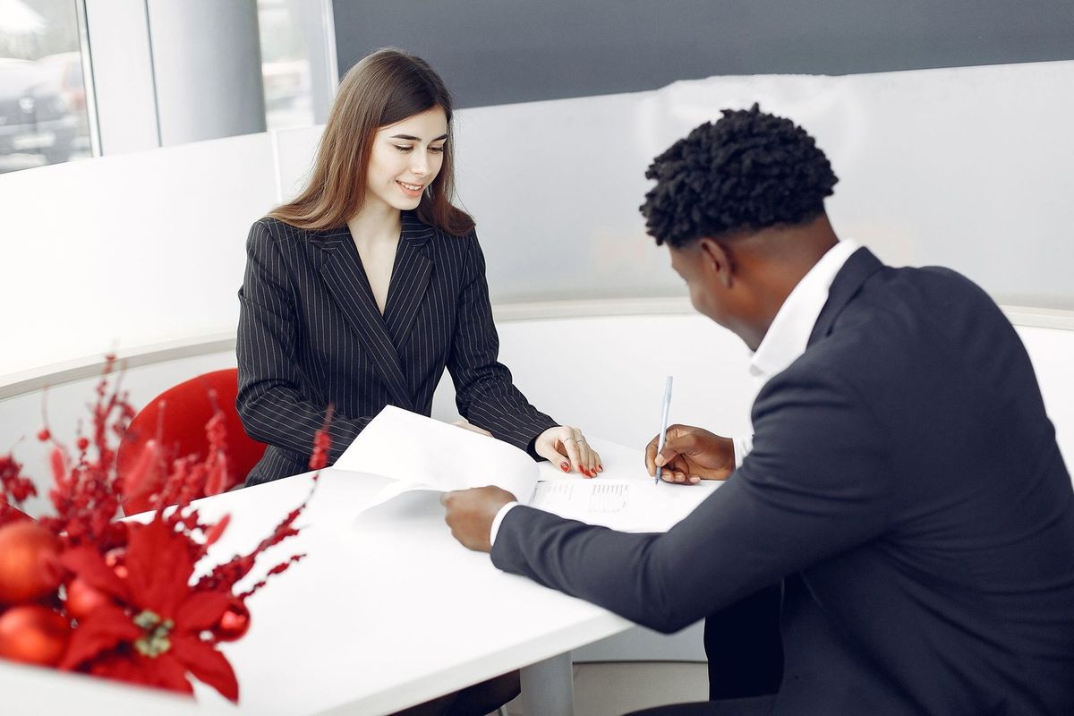 Deux personnes en réunion, en train de signer des documents, entourées de décorations de Noël Deux personnes en réunion, en train de signer des documents, entourées de décorations de Noël