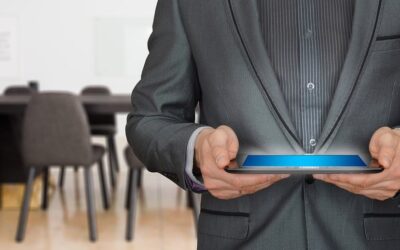 Homme en costume noir tenant une tablette lumineuse dans une salle de réunion