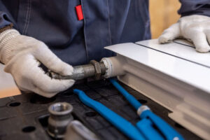 Plombier chauffagiste installant un raccord de radiateur avec précision lors d'une intervention à Toulouse