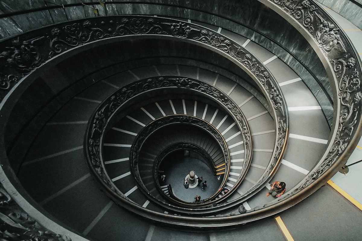 Un escalier en spirale à l'intérieur d'un bâtiment avec quelques personnes