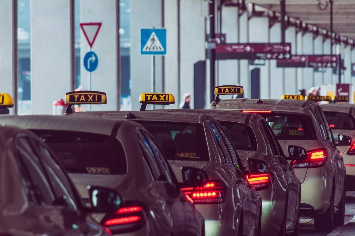 Une rangée de taxis avec panneaux lumineux attendent au point de départ