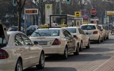 Une rangée de taxis blancs attend au feu rouge