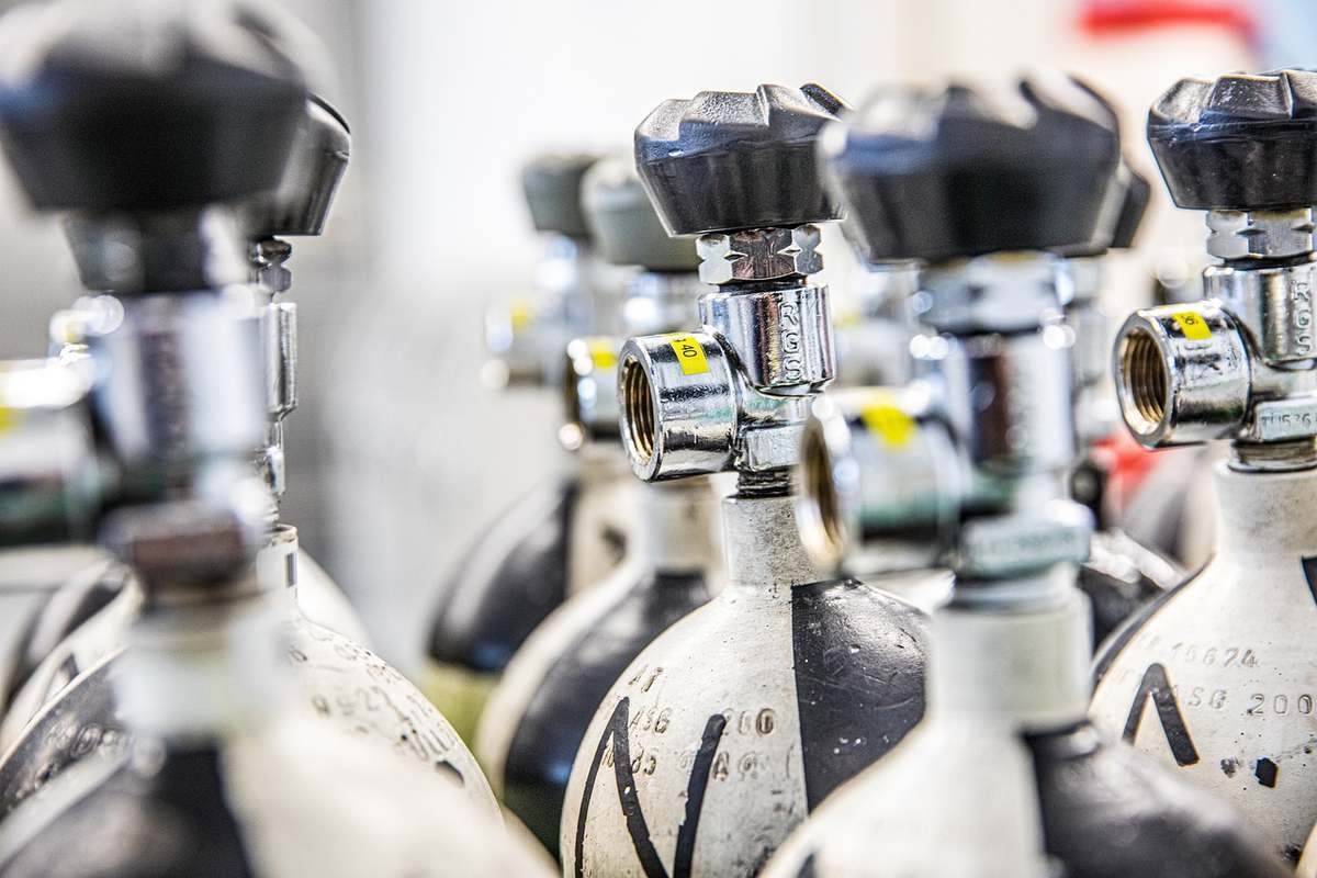 Cylindres de gaz avec valves et étiquettes jaunes alignés en rangée