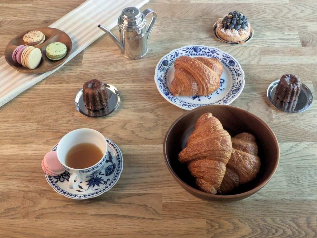 Table en bois avec pâtisseries, croissants, théière, tasses et saucers