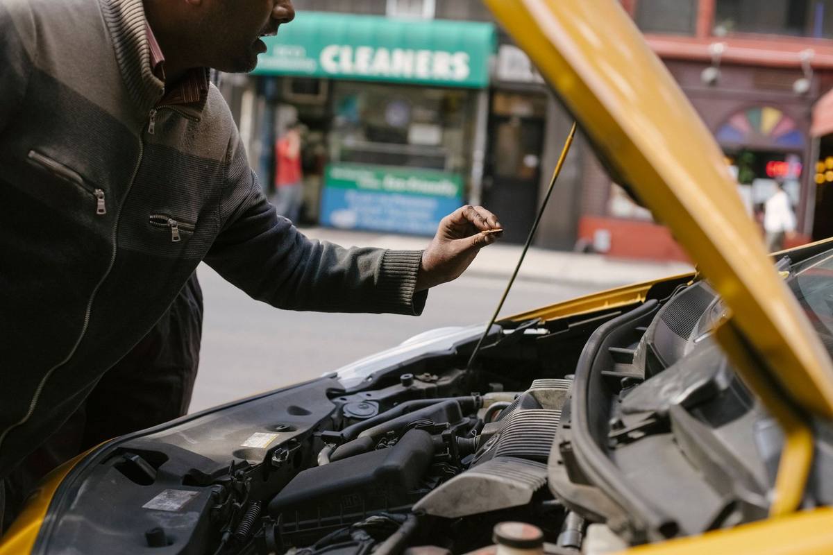 Homme vérifie le moteur d'une voiture jaune stationnée près d'un nettoyage
