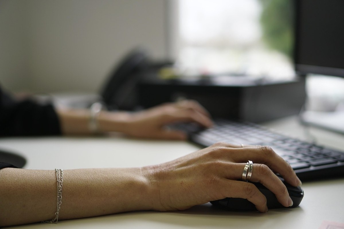Une femme utilise une souris d'ordinateur à son poste de travail professionnel