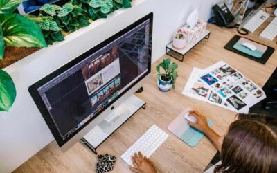 Femme travaillant sur un ordinateur avec feuilles photos et plantes à proximité