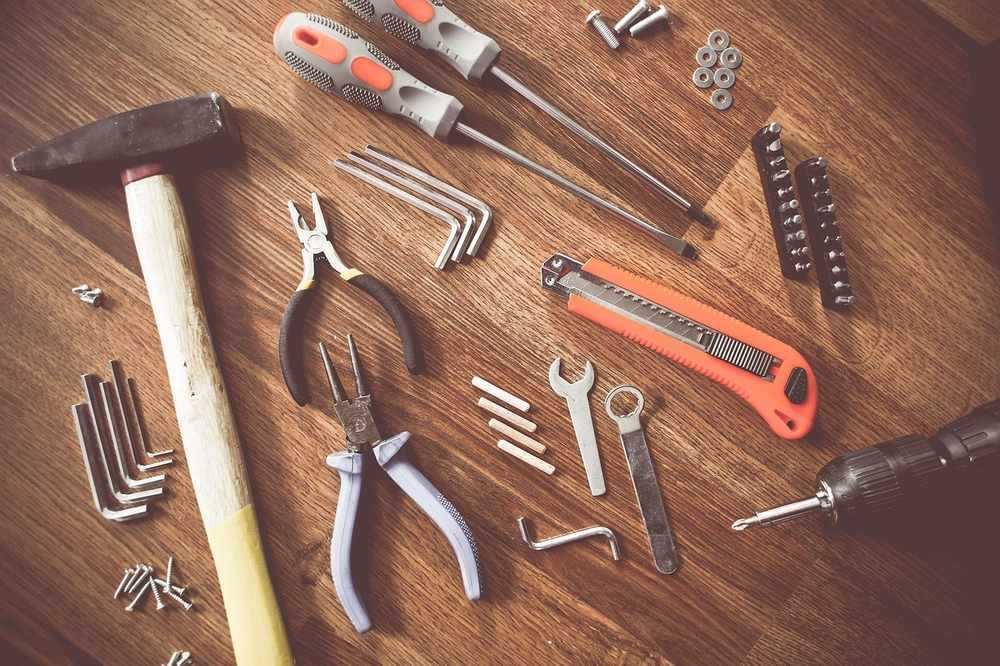 Outils de bricolage sur une surface en bois, avec des pinces, des tournevis, une lime, des clous et des vis Outils de bricolage sur une surface en bois, avec des pinces, des tournevis, une lime, des clous et des vis