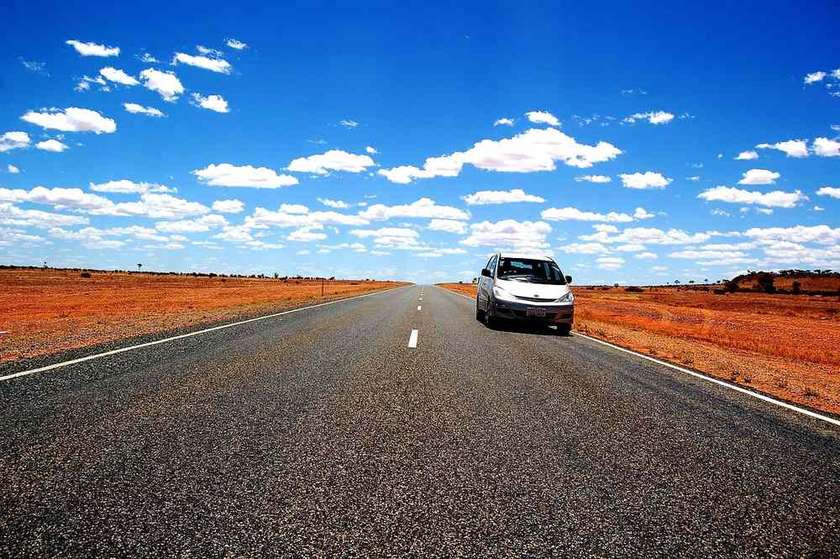 Voiture sur une route asphaltée, champ de blé à droite, ciel bleu avec nuages Voiture sur une route asphaltée, champ de blé à droite, ciel bleu avec nuages